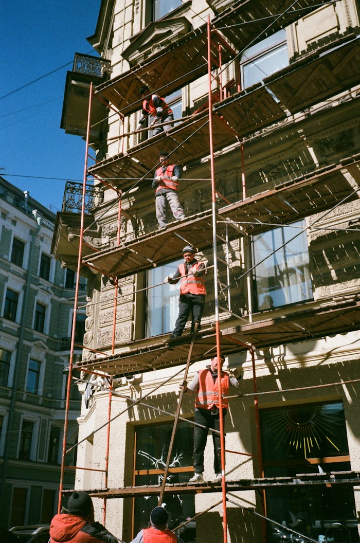 Crafting Captivating Headlines: Your awesome post title goes here Construction workers on scaffolding renovating a building facade on a sunny day.
